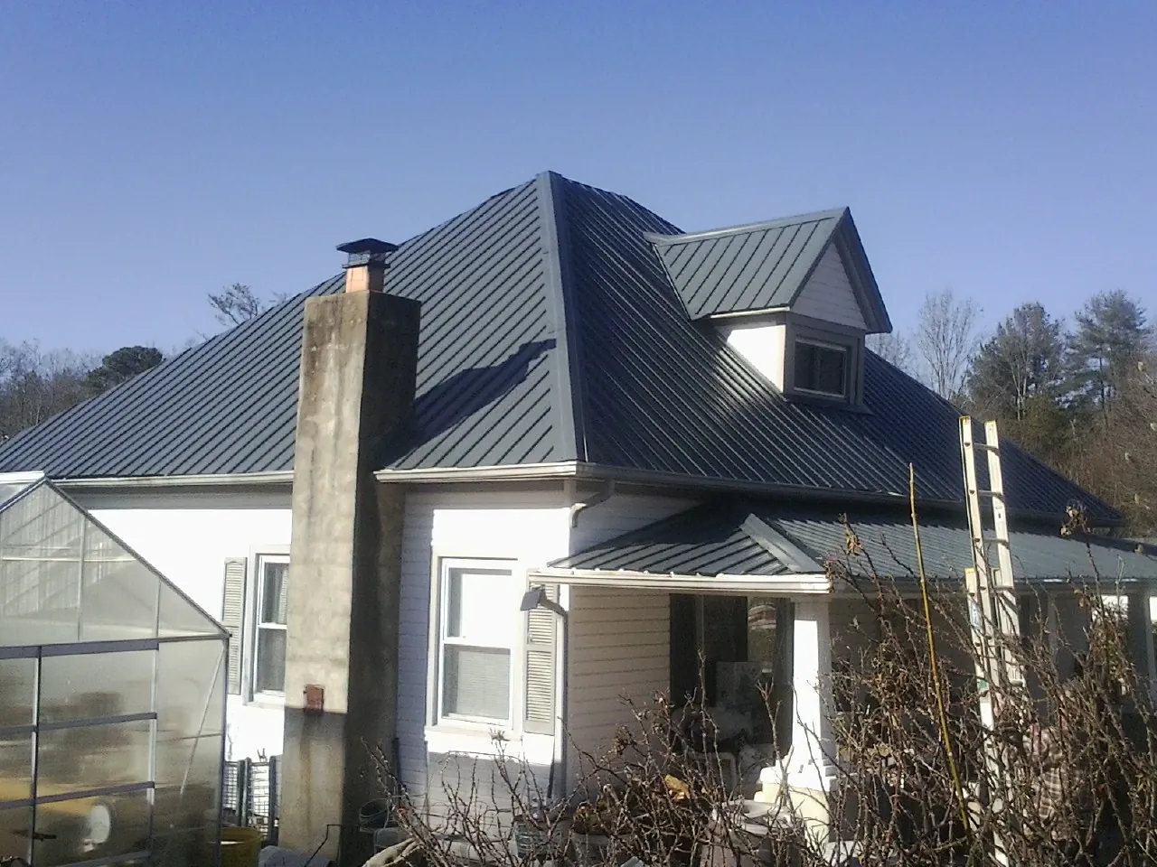 Dark blue standing seam metal roof on a white farmhouse with dormer — Slate & Tile Roof Repair by Roofing Brothers in Lake Harmony