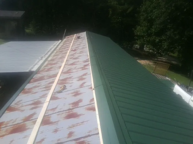 Old rusted panels beside newly installed green metal roofing — Wind Damage Roof Repair by Roofing Brothers in Lake Harmony
