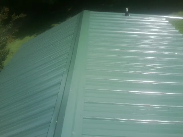 New green metal panels meeting at the ridge of a roof — Flat Roof Repair work by our crew in Lake Harmony