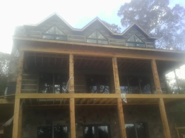 Dormers and porch framing on a large log home under construction — Roof Coating work by our crew in Lake Harmony