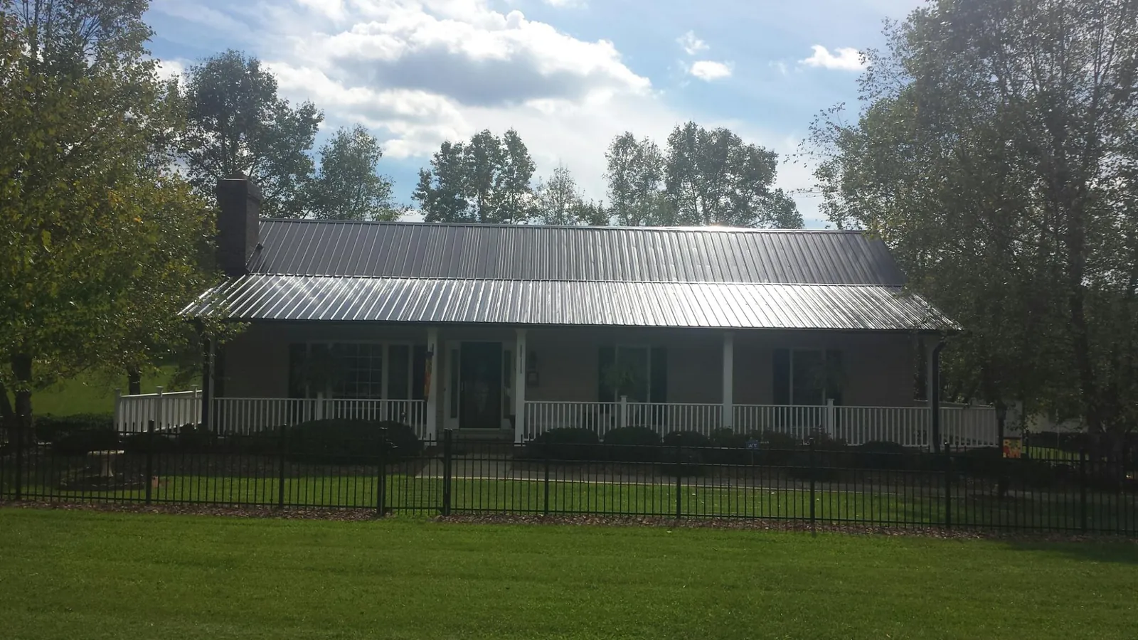 Gray metal roof on a brick ranch with a full width front porch — Gutter Guard Installation work by our crew in Lake Harmony