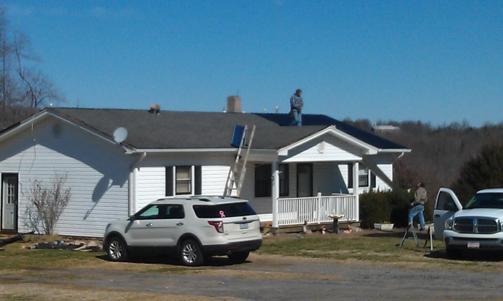 Roofers stripping shingles from a white ranch house roof in Lake Harmony