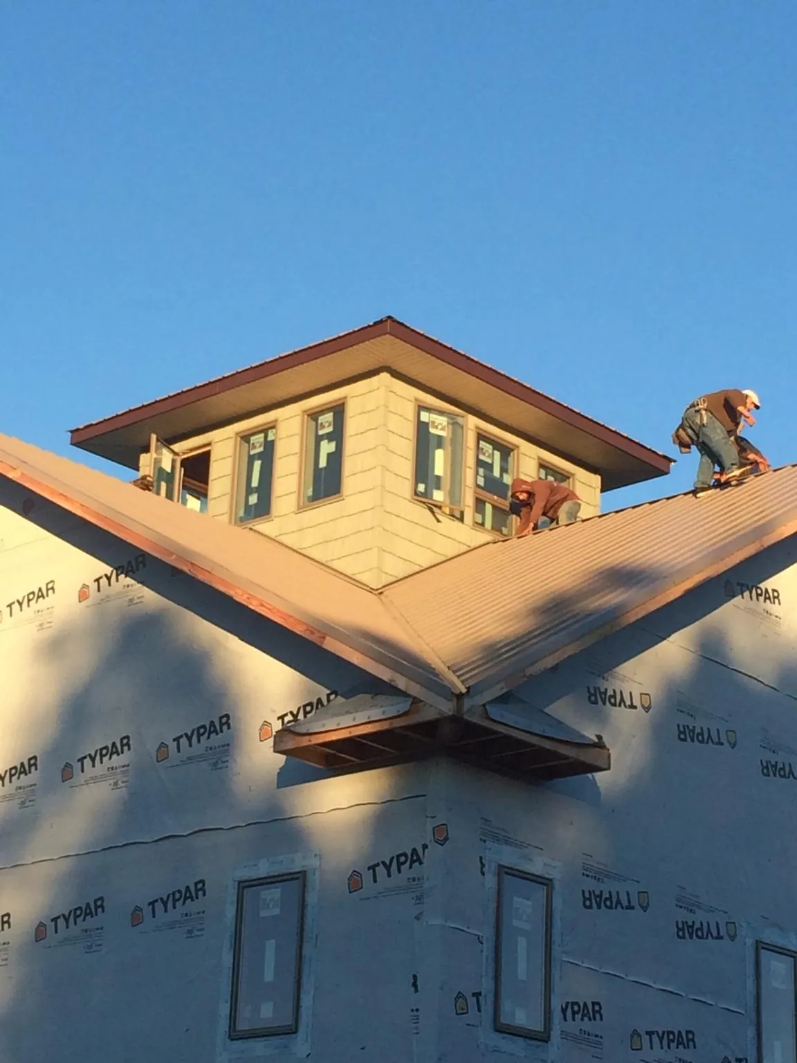 Roofers working around a rooftop cupola on a new metal roof at sunset — Roof Waterproofing in Lake Harmony by Roofing Brothers